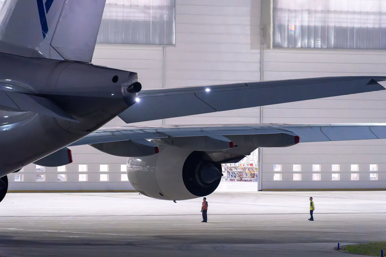 Flugzeug in einer Wartungshalle, Techniker prüfen Triebwerk und Leitwerk