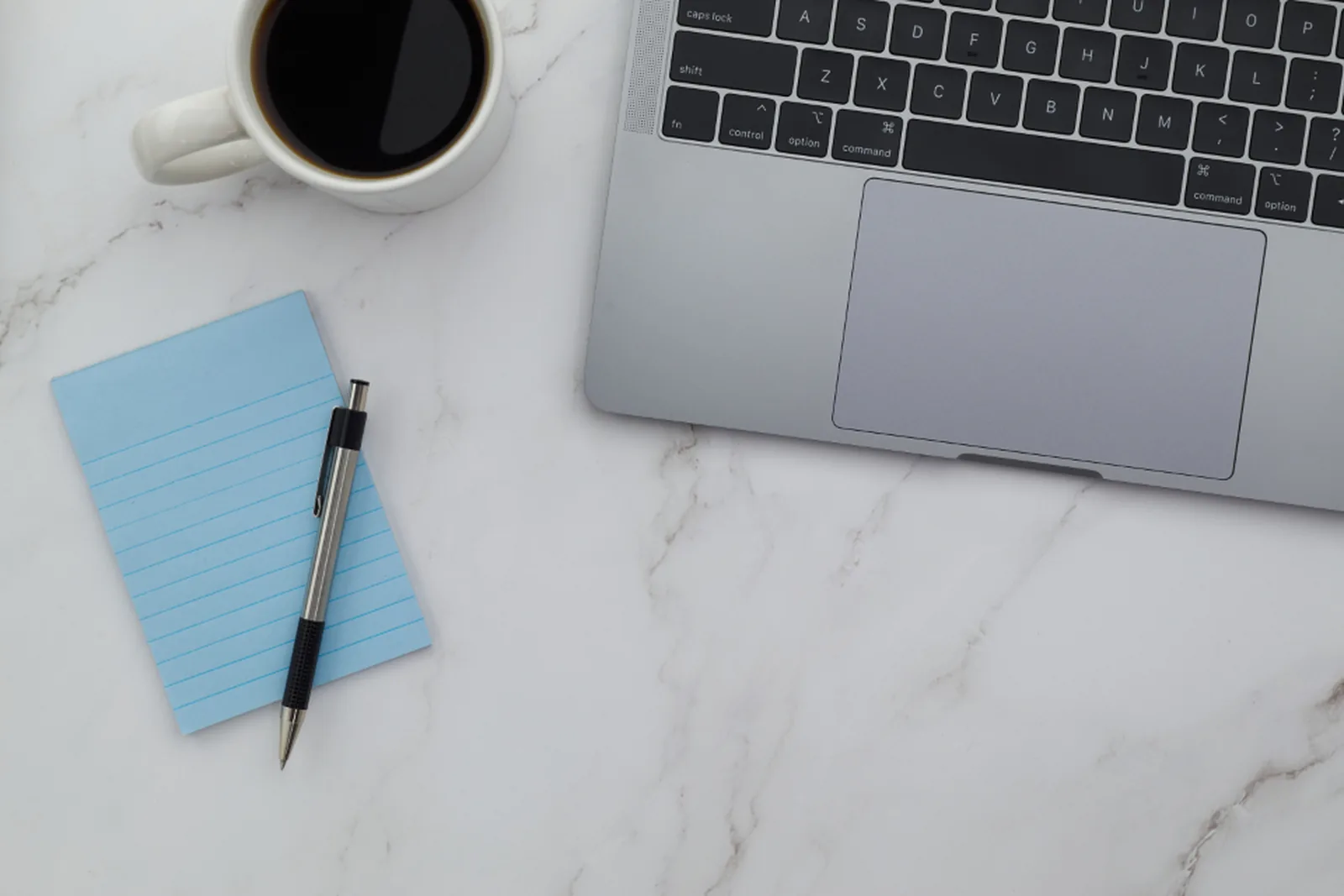 Arbeitsplatz mit Notizbuch und Laptop für die Vorbereitung des Förderantrags