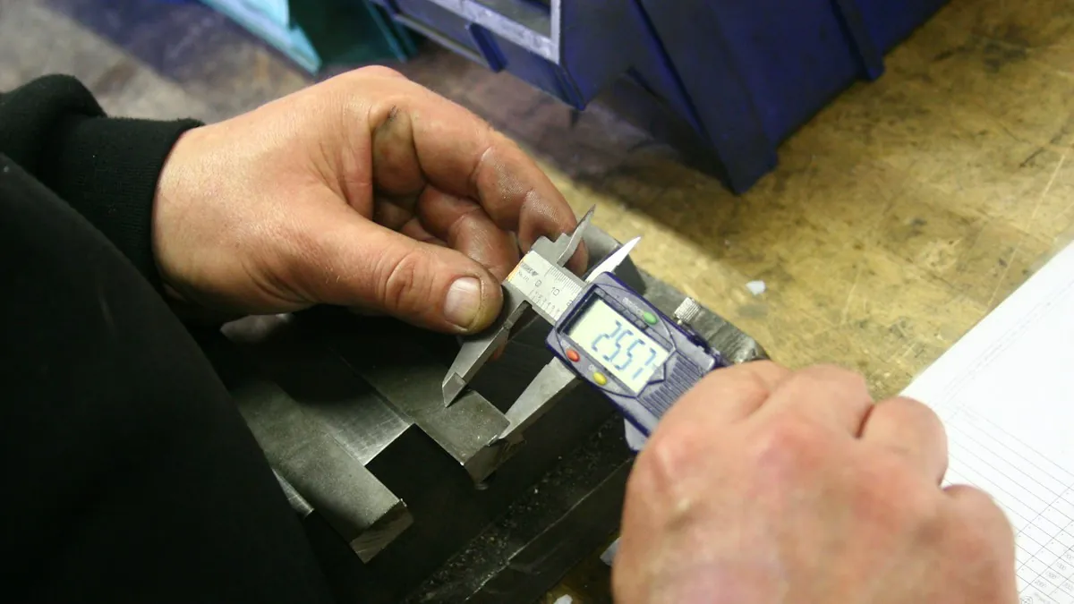 Hände messen ein Metallteil mit einem digitalen Messschieber an einer Werkbank