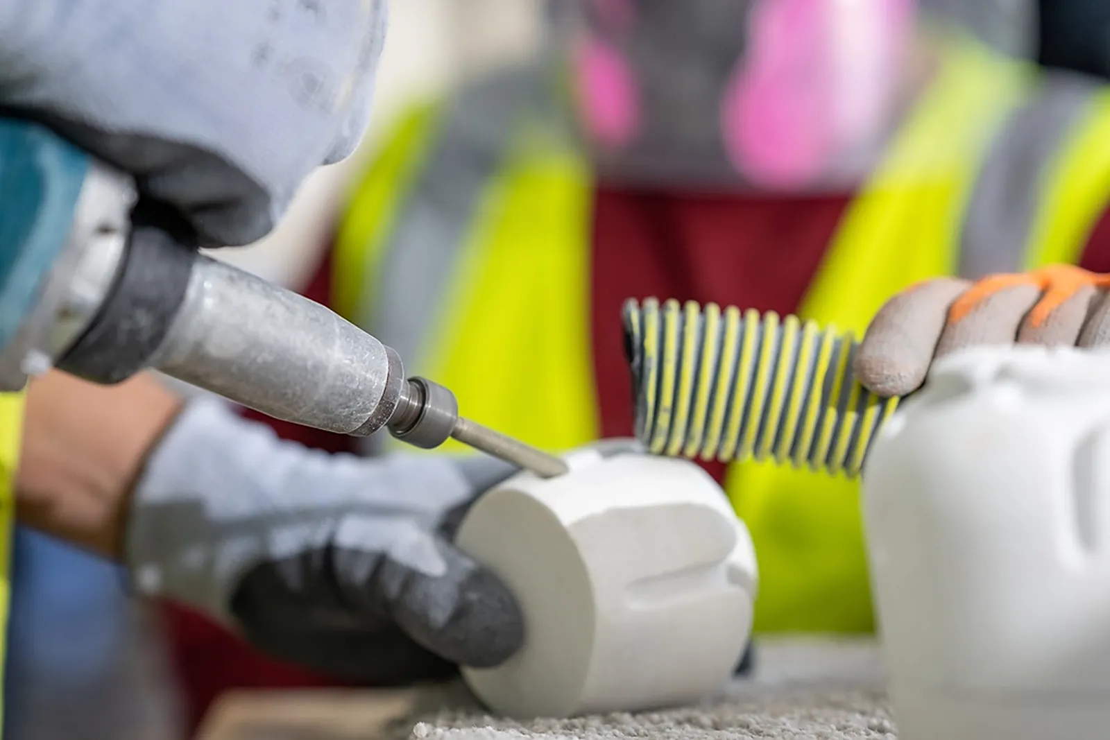 Montagearbeit an einem Bauteil mit Druckluftwerkzeug und Schutzausrüstung
